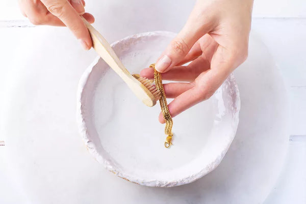 Un bracelet en or nettoyé délicatement avec une brosse à dent blanche